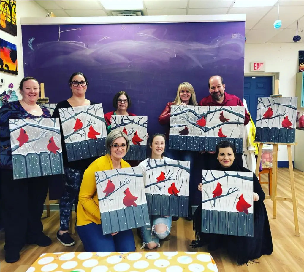 Friends showing their cardinal paintings at the end of a paint night